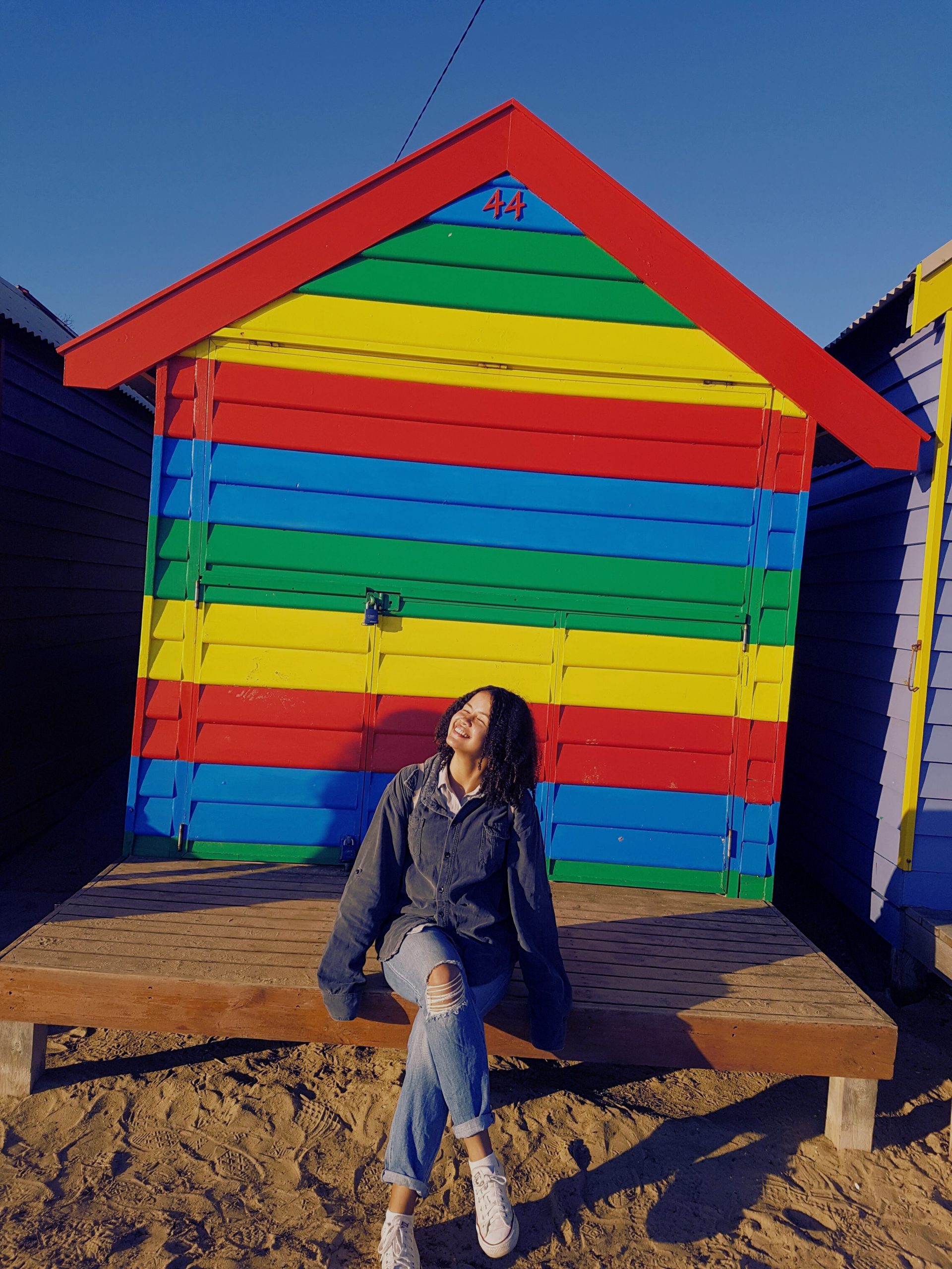 Woman smiling towards sun in front of beach shed